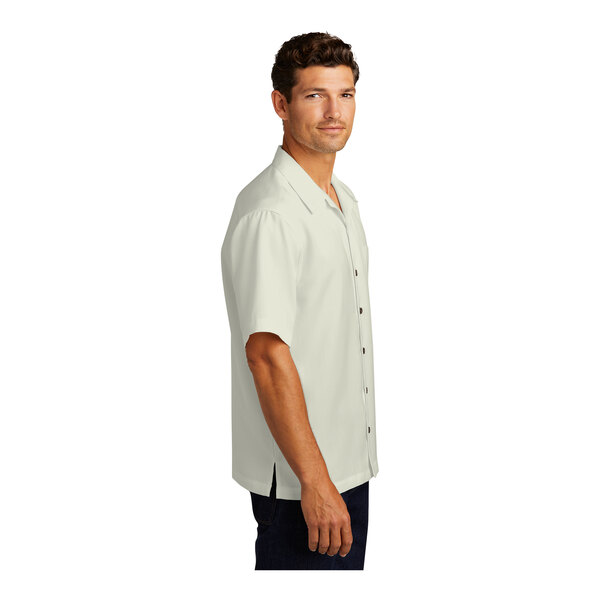 A man wearing a Port Authority unisex short sleeve camp shirt in white.