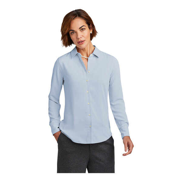 A woman with short hair wearing a Brooks Brothers blue long sleeve full-button shirt.
