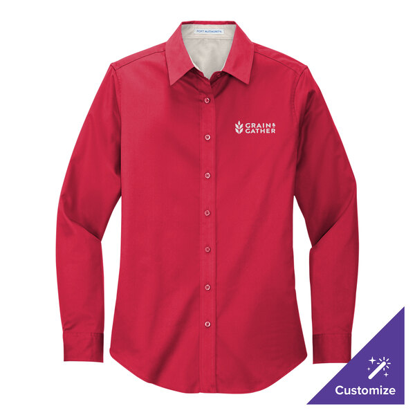 A medium red Port Authority long sleeve dress shirt on a counter with a company logo.