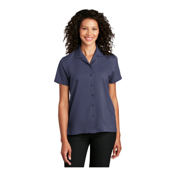 A woman wearing a Port Authority navy blue short sleeve staff shirt.