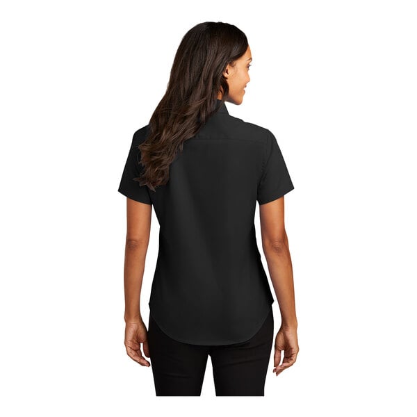 A woman wearing a black Port Authority short sleeve dress shirt with a black collar.