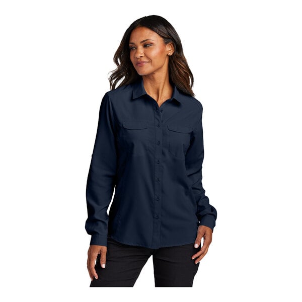 A woman wearing a navy short sleeve Port Authority shirt.