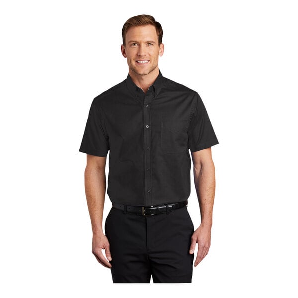 A man wearing a black and light stone Port Authority dress shirt with short sleeves.