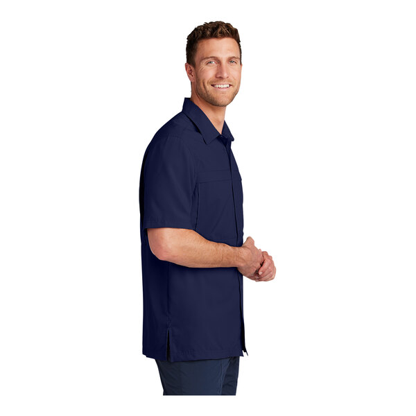 A man wearing a navy Port Authority short sleeve performance shirt.