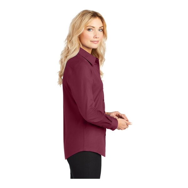 A woman with long blonde hair wearing a Port Authority burgundy long sleeve shirt.