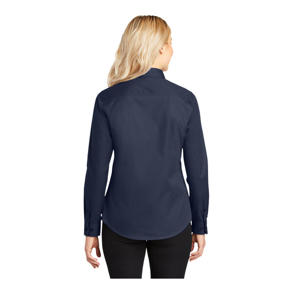 A woman wearing a Port Authority navy blue long sleeve dress shirt.