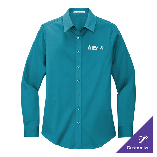 A teal Port Authority women's long sleeve dress shirt with the logo on the counter.