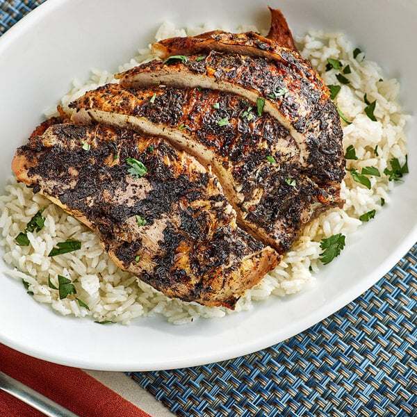 A plate of chicken and rice with Walkerswood Mild Jerk Seasoning on a table.