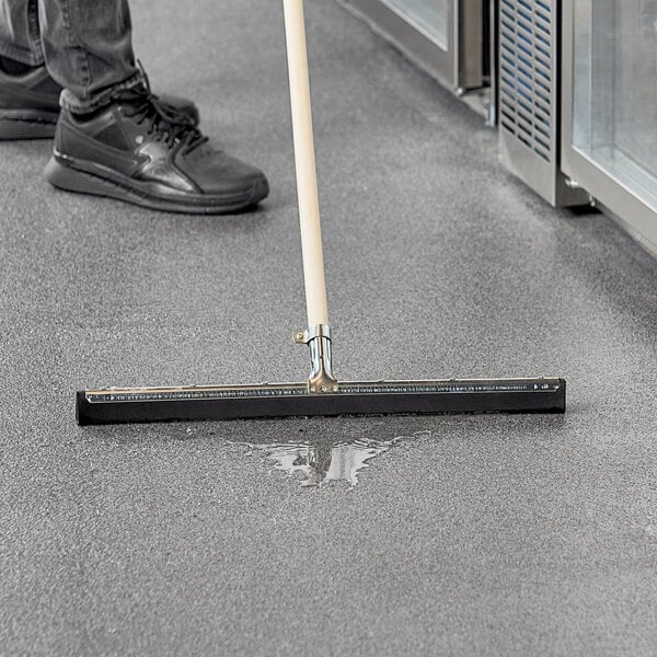 A person cleaning the floor with an Ettore 22" floor squeegee.