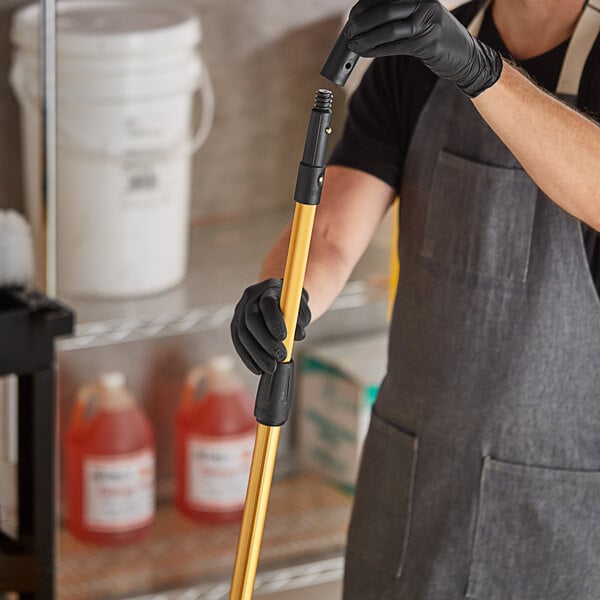 A person holding a yellow handle extension pole.