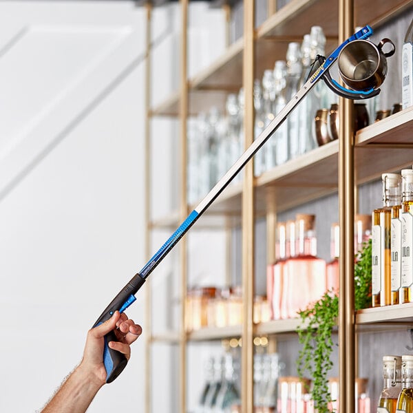 A hand holding a blue and black Ettore Barracuda reaching tool.
