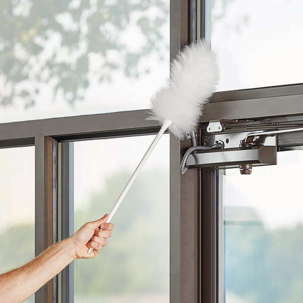 A hand using an Ettore lambswool duster to clean a window.