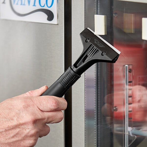 A hand using an Ettore heavy-duty scraper to clean a surface.