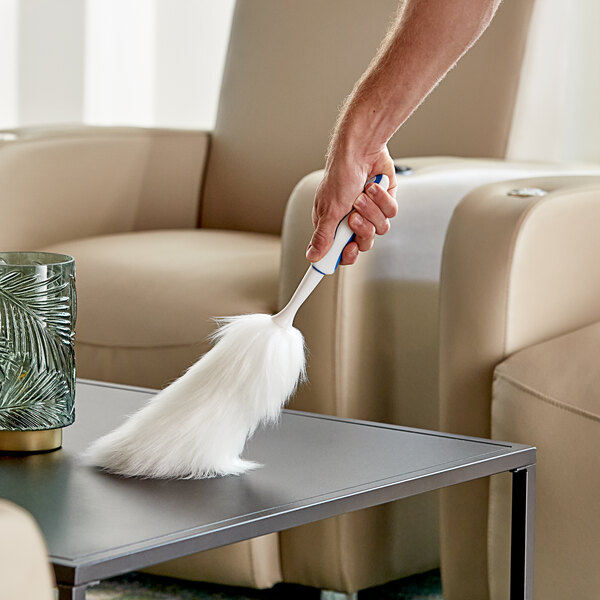 A hand holding a white fluffy Ettore lambswool duster.