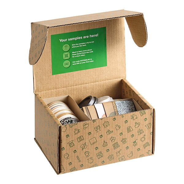 A cardboard box with a green ribbon and a green lid with a stack of New Roots paper hot cups, lids, and sleeves inside.