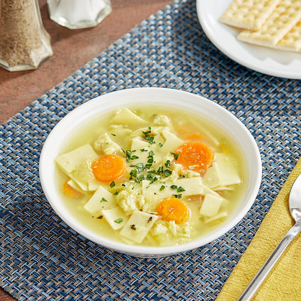 A bowl of Blount Fine Foods chicken noodle soup with carrots and crackers.