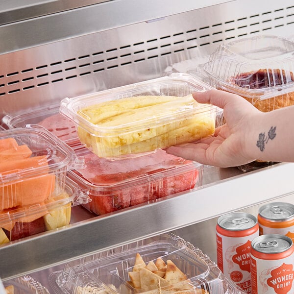 A hand holding a Choice TamperSafe clear plastic container with food in it.