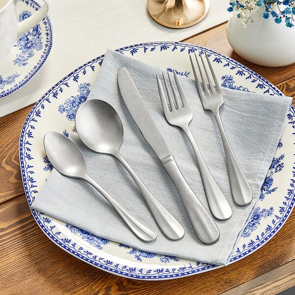 A white plate with Acopa Josette stainless steel flatware on it.