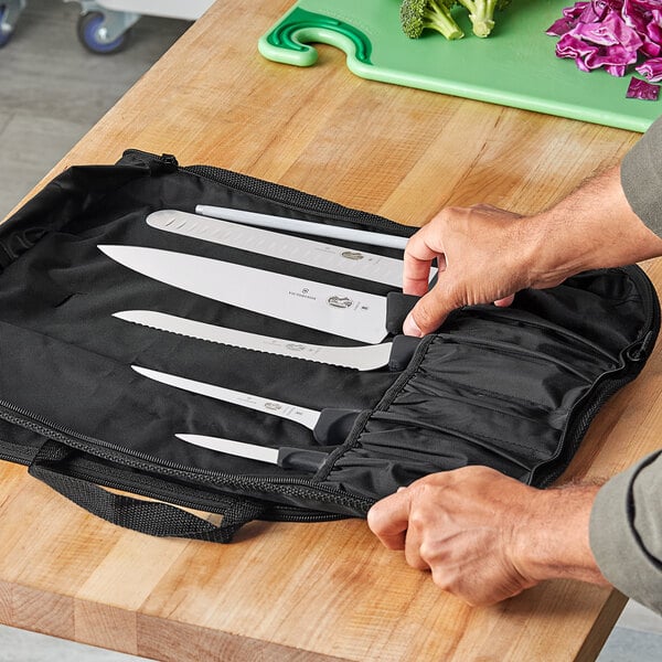 A hand holding a Victorinox 7-piece knife set in a bag.