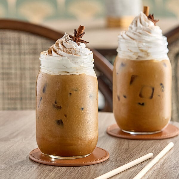 A glass jar of brown Dr. Smoothie Classic Chai Beverage Mix on a table in a coffee shop.