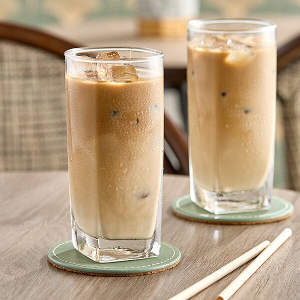 Two glasses of Dr. Smoothie Cafe Essentials Vanilla Latte on a table with coasters.