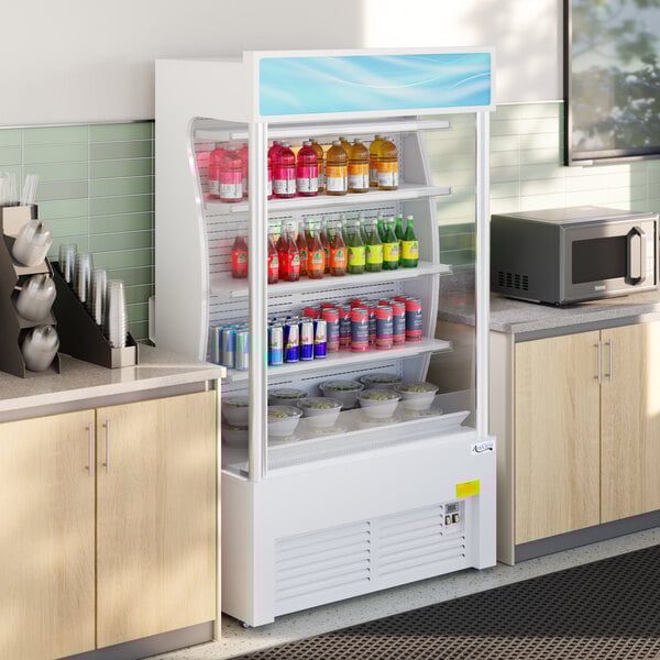 A white refrigerated air curtain merchandiser stocked with drinks and food items.