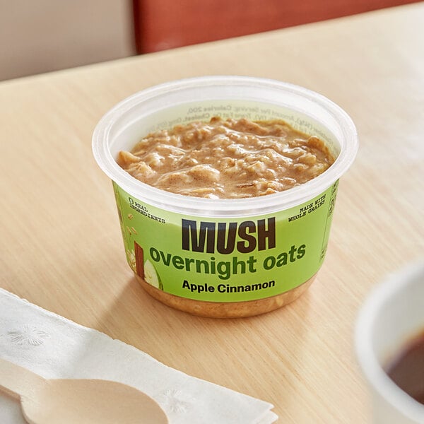 A container of Apple Cinnamon Oats with a green label on a table.