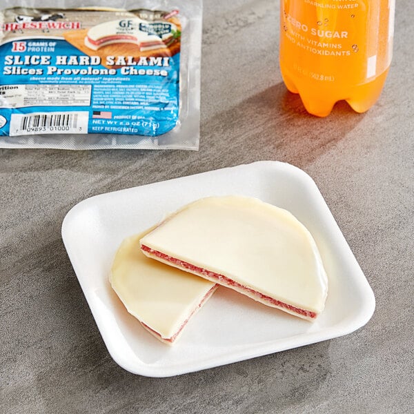 A Cheesewich salami and provolone cheese sandwich on a plate next to a bottle of soda.