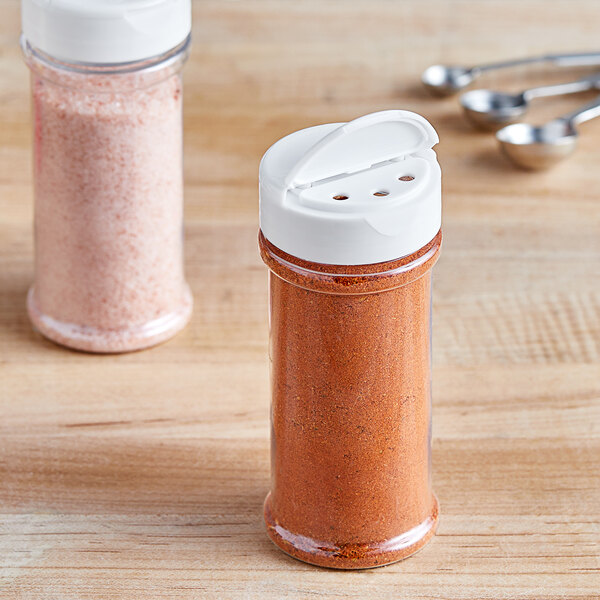 Two 8.4 oz. round plastic spice containers with white lids holding powder and spoons.