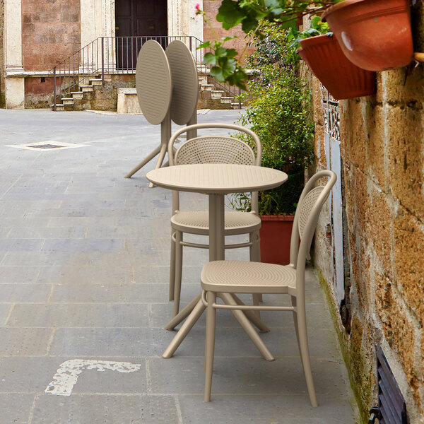 A Siesta Sky round taupe foldable table and chairs on a patio.