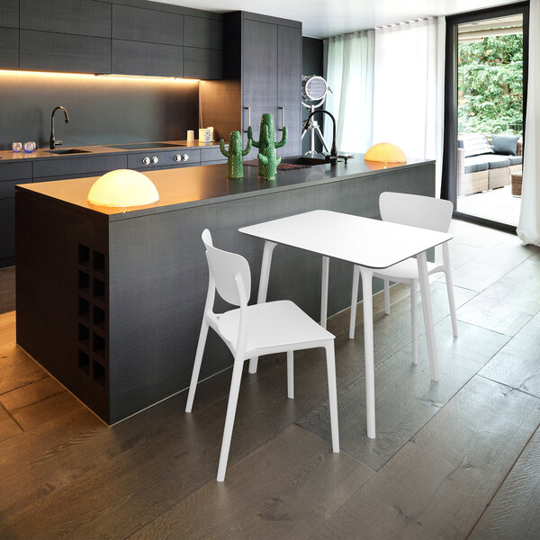 A white Siesta Monna resin outdoor dining chair next to a white table.