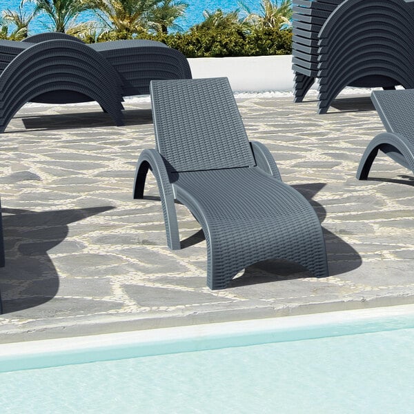 Siesta Miami dark gray Wickerlook resin outdoor chaise lounges next to a pool.