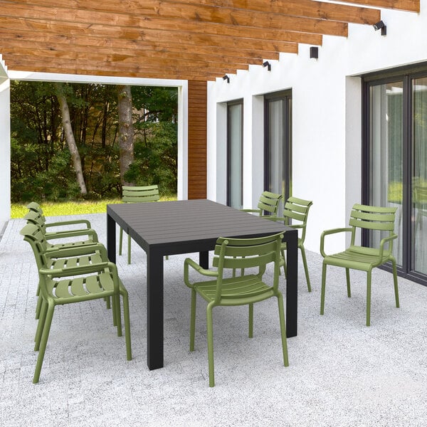 A group of Siesta Paris olive green resin outdoor dining arm chairs on a patio.