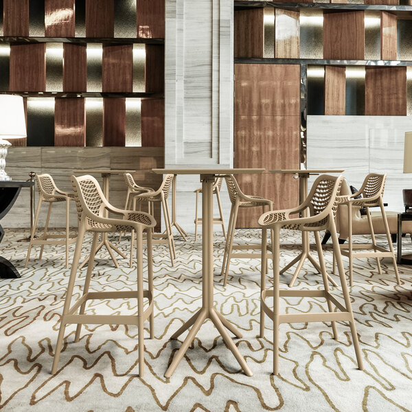 A Siesta Sky taupe bar height foldable table in a room with chairs.