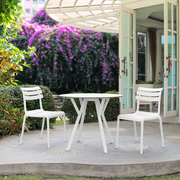 A white resin Siesta Helen outdoor dining chair on a patio.