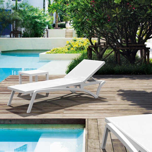 A white Siesta Pacific chaise lounge next to a pool.