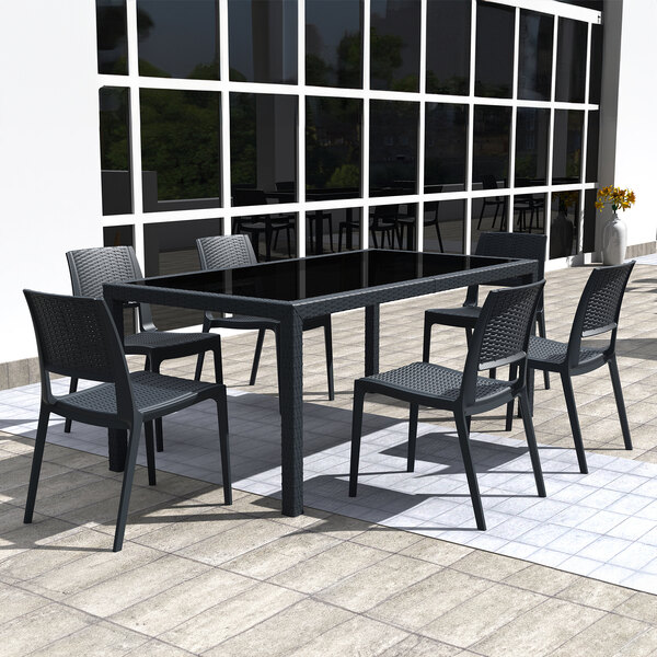 A dark gray Siesta Verona Wickerlook outdoor dining chair on a patio with a table and chairs.
