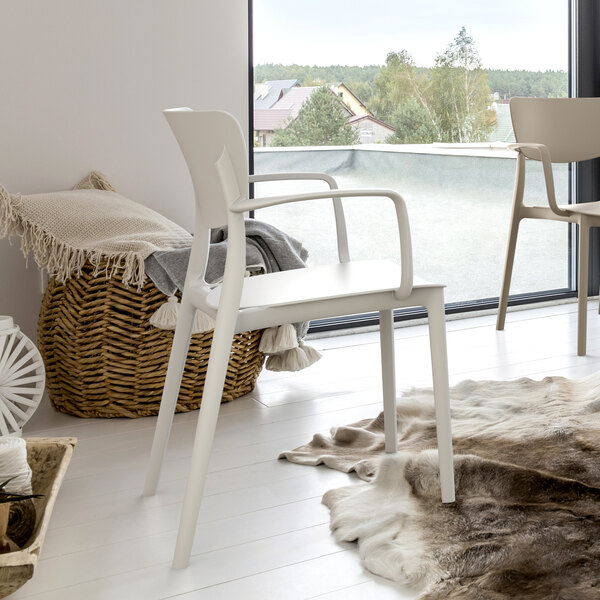 A white chair next to a fur rug on a white floor.