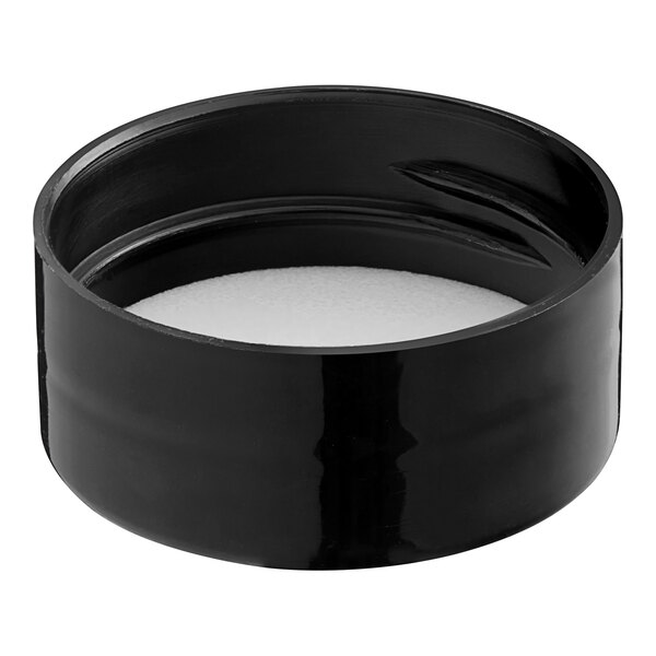 A black round plastic spice container with a white lid with a foam liner.
