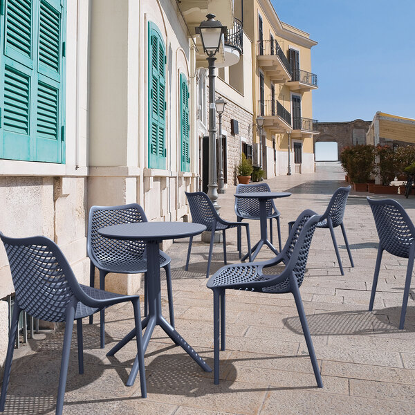 A Siesta Sky dark gray foldable table on an outdoor patio with blue chairs.