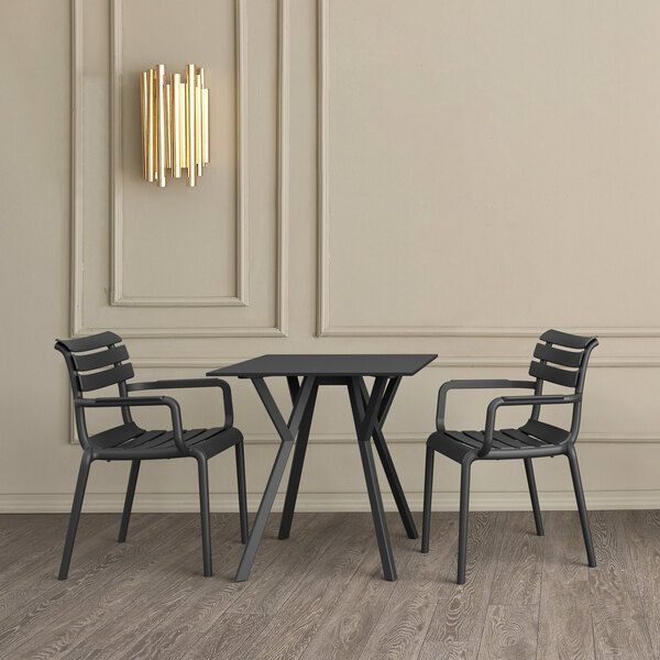 A black Siesta Paris resin outdoor dining chair on a table on an outdoor patio.