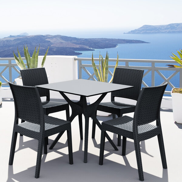 A dark gray Siesta Florida wickerlook outdoor dining chair on a patio table overlooking water.