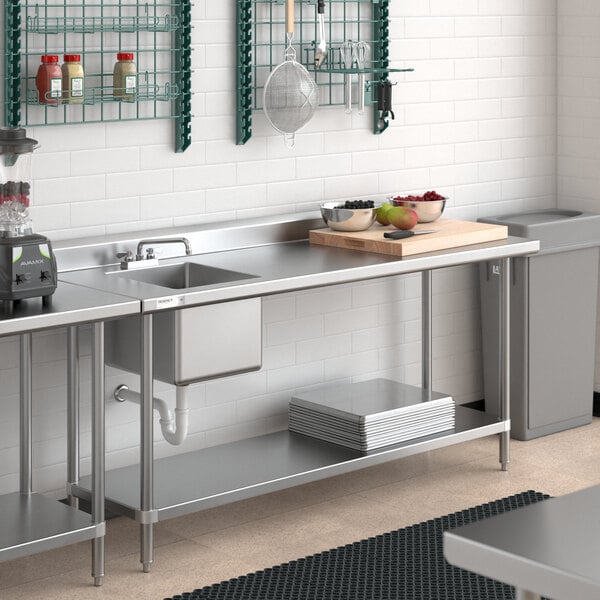 A Regency stainless steel work table with a sink on the left in a kitchen with a stainless steel sink and counter.