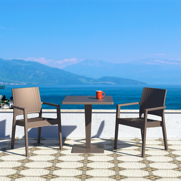 A Siesta Ibiza brown wickerlook resin outdoor dining arm chair on a patio.