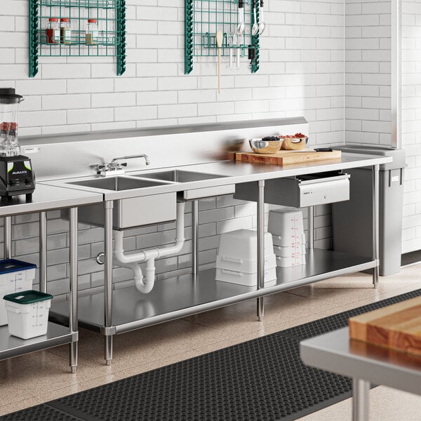 A Regency stainless steel work table with sinks on a counter in a kitchen.