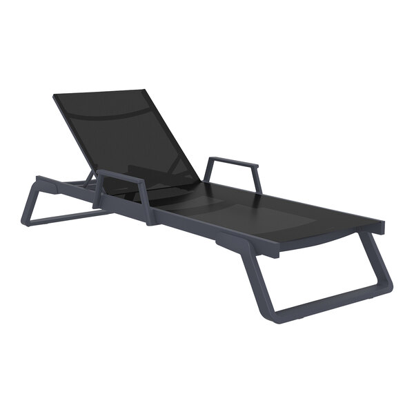 A dark gray resin Siesta Tropic outdoor arm chaise lounge with black sling on a table.