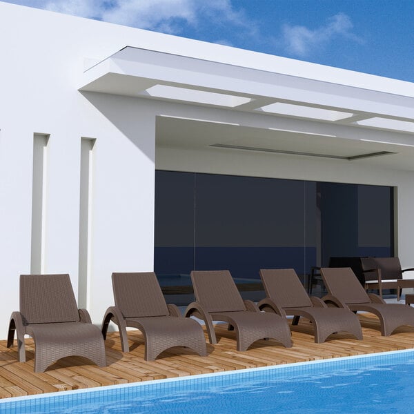 A brown Siesta Miami Wickerlook chaise lounge chair on a wood deck.