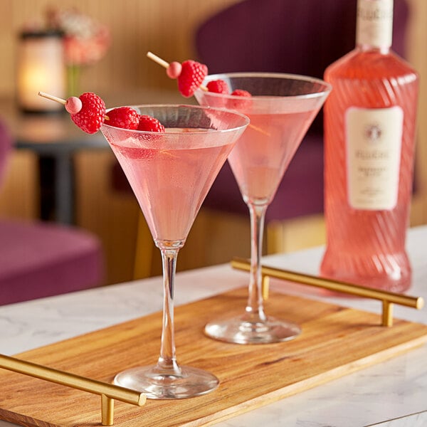 A wooden tray with two glasses of Fluere Non-Alcoholic Raspberry Blend Pink Gin with raspberries.