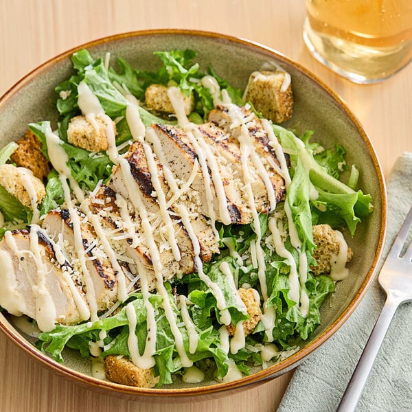 A salad with chicken and Ken's Caesar Dressing on a plate.