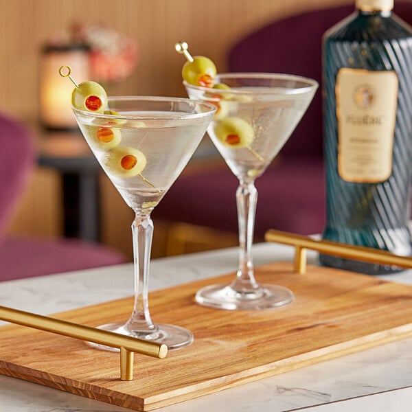 A pair of martini glasses with olives on a table in a cocktail bar.